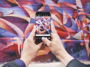 Person takes photo of some bright street art on their phone